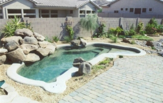 Freeform spool with a rock waterfall and paver decking