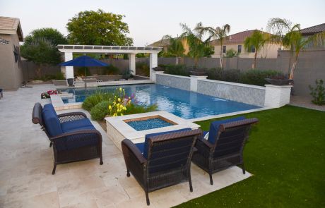 Patio seating around a fire table beside a pool with sheer descents and a pergola