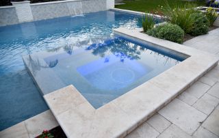 12 Pool with an attached travertine-edged spa and planters