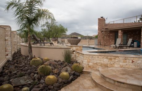 Desert-landscaped backyard with barrel cacti beside a pool and raised spa