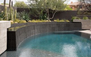 4 Modern pool with a curved dark-tile water wall and desert plants