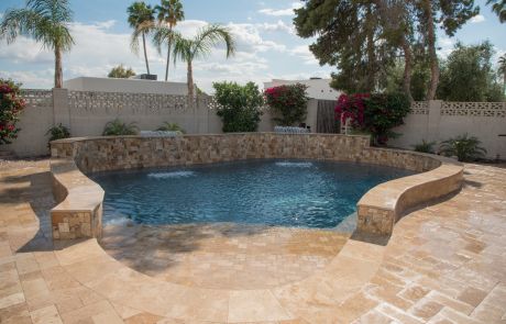 Pool with a curved stacked-stone raised wall and travertine decking