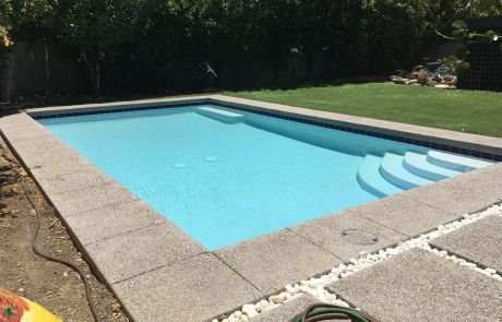 Rectangular pool with entry steps and exposed-aggregate decking during renovation