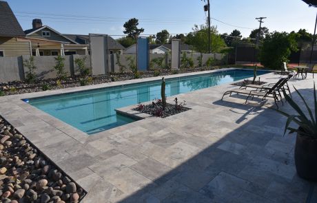 Long rectangular pool with travertine decking and loungers