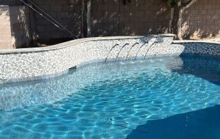 Pool with a mosaic glass-tile raised wall and spillway jets