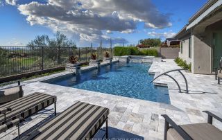 Pool with handrail steps, travertine decking and loungers
